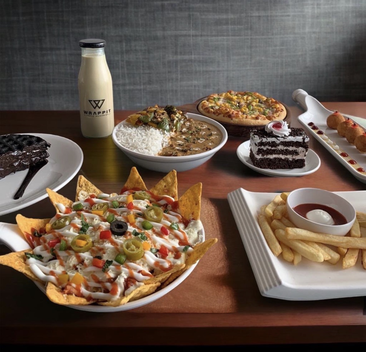 Wrappit signature spread of nachos, pizza, curry, cake and fries